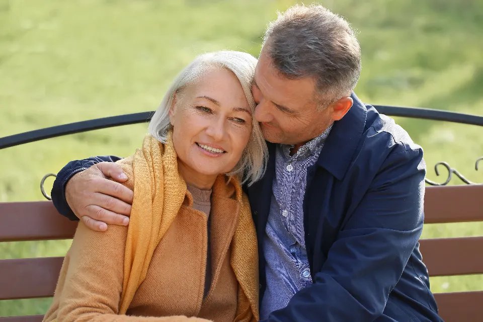 An older couple sitting close together on a park bench
