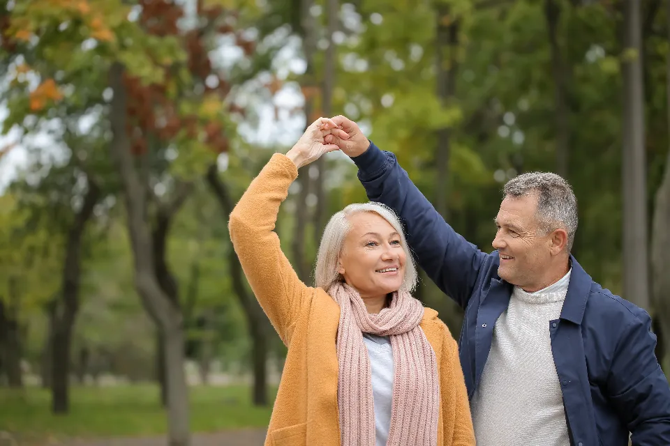 An older couple dancing in a Topeka park among autumn trees